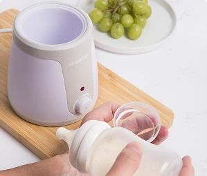 Snookums baby bottle warmer beside baby bottles and feeding accessories on a kitchen counter