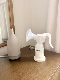 Snookums Manual Breast Pump with breast shield and handle on a bedside table