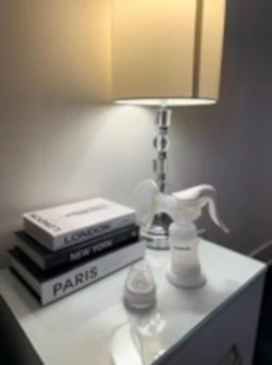 Snookums Manual Breast Pump with baby bottles and feeding accessories on a bedside table